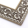 A large, reverse curve profile frame with an intricate leaf design bordered by a geometric outer edge and beaded inner lip. A matte grey base, with silver foil patina along the topmost points of the design. The beading is gold foil. Strong, solid wood construction.
2.75 " width: ideal for large and extra large (oversize) images.